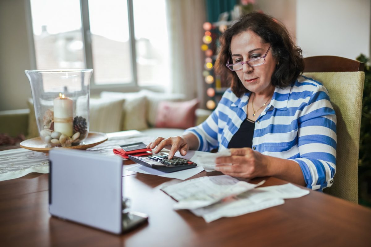 Mature woman calculating retirement income at laptop